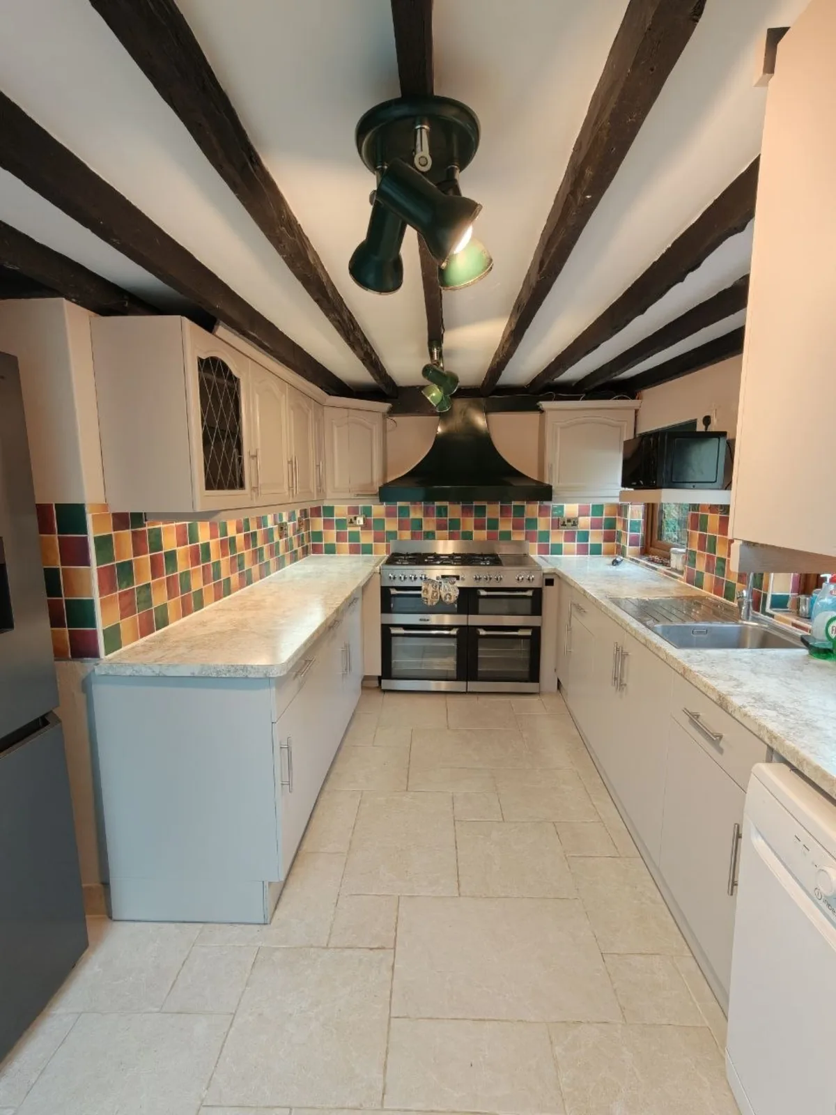 Cream kitchen with exposed beams, marble-effect worktops and a range cooker