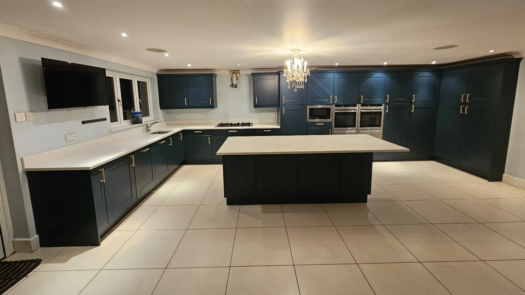 A large kitchen resprayed in deep navy with pale stone worktops