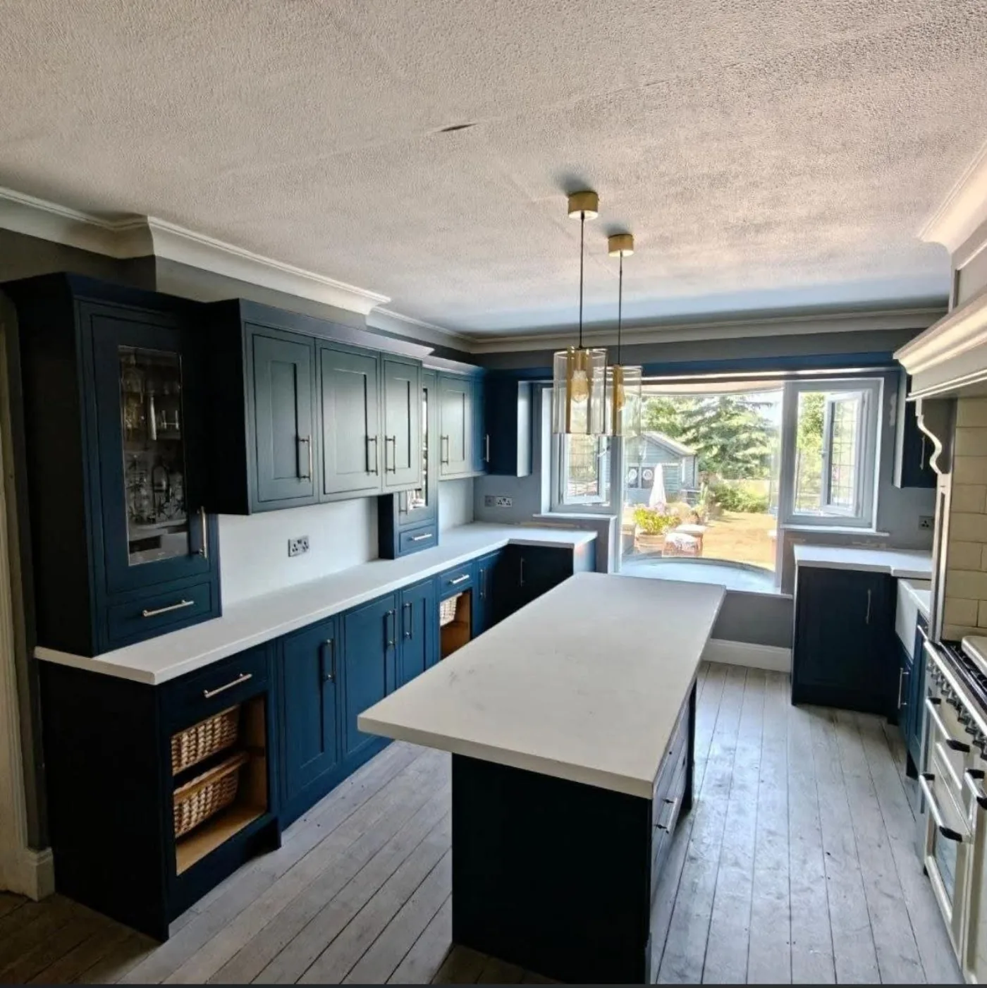 Shaker kitchen resprayed in teal blue with a matching island and white quartz worktops